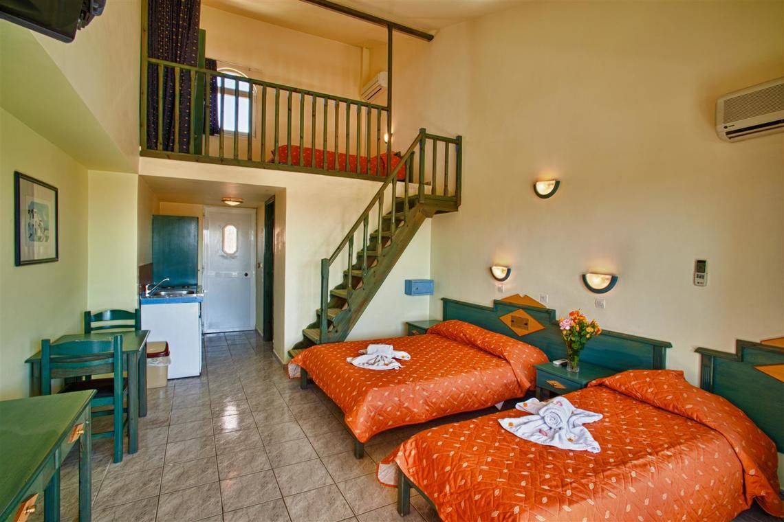 Zimmer im Ilios K. Village Resort mit zwei Betten, Tisch, Stühlen und einer Treppe