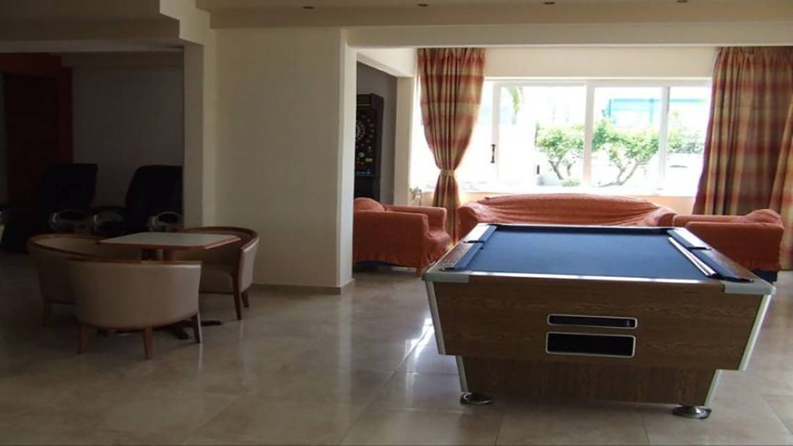 Pooltisch in der Lobby des Ilios K. Village Resort, umgeben von Sofas und Sesseln.