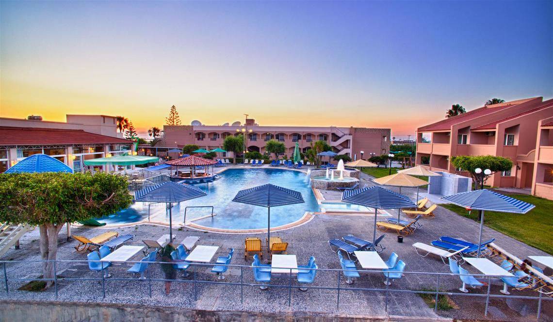 Außenbereich des Ilios K. Village Resorts mit Swimmingpool, Sonnenliegen und Sonnenschirmen