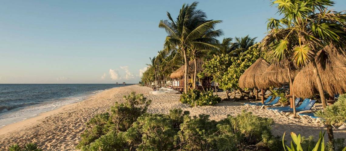 Strand des Grand Riviera Princess Hotels mit Sonnenliegen und Strohhütten