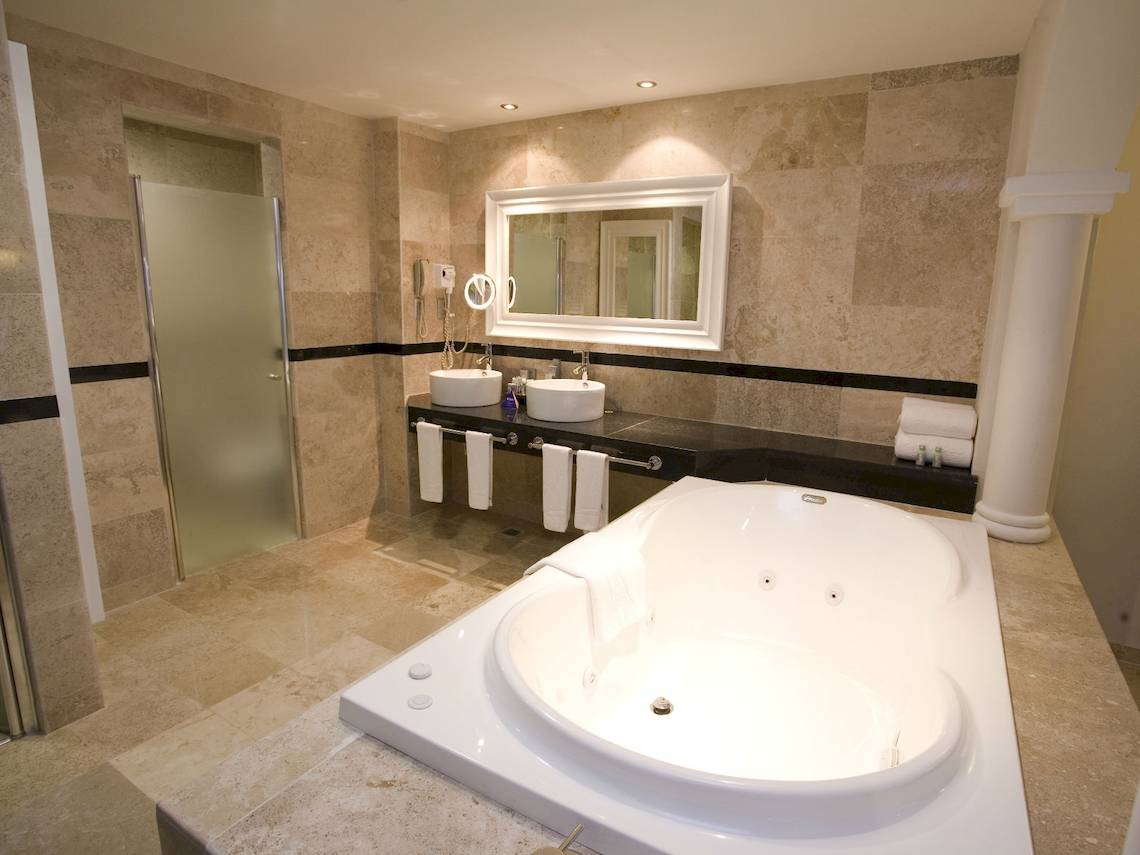 Badezimmer im Grand Riviera Princess Hotel mit Badewanne, Spiegel und Waschbecken.