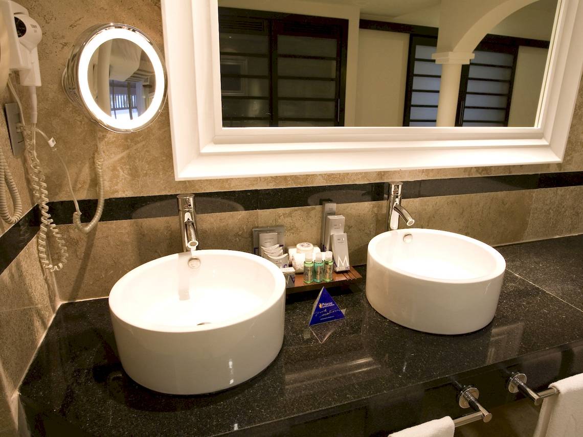 Badezimmer im Grand Riviera Princess Hotel mit zwei Waschbecken, Spiegel und Handtuecher.