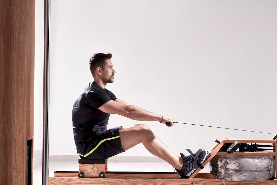 Ein Mann trainiert auf einem Rudergerät im Fitnessstudio.