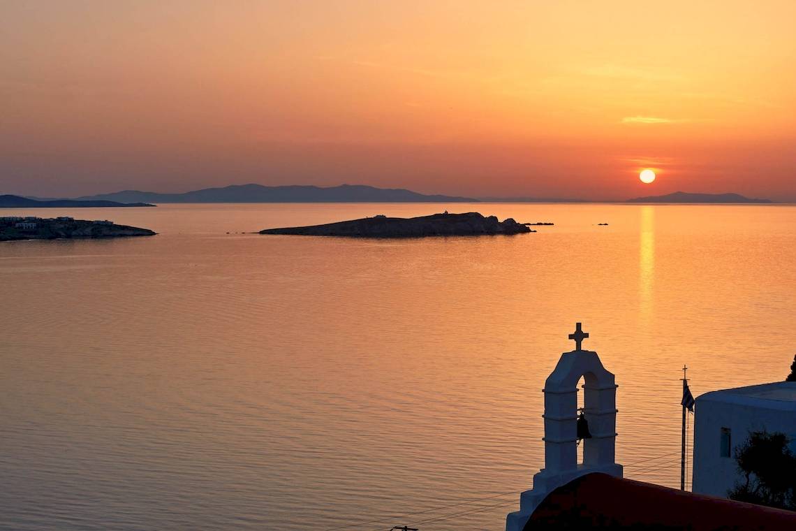 Sonnenuntergang am Meer mit einer Kirche im Vordergrund.