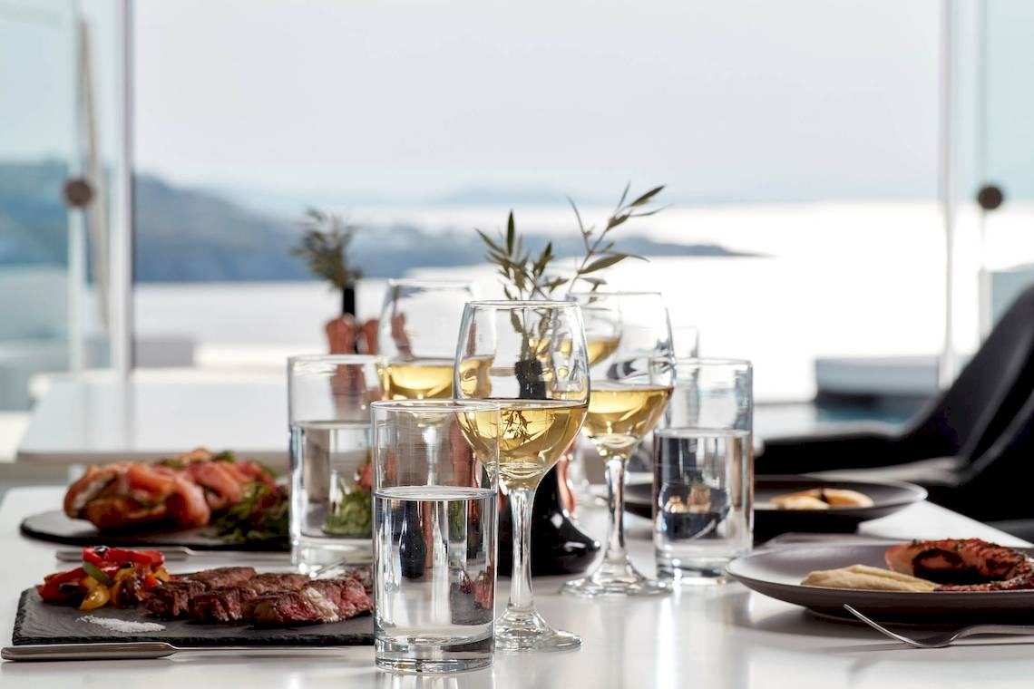 Essen auf dem Tisch im Absolute Mykonos Suites & More Hotel mit Getränken und Aussicht auf das Meer.