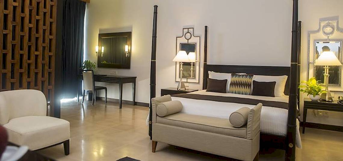 Schlafzimmer im Blue Water Hotel und Spa mit vierposterbett, kissen, nachttischen und lampen.