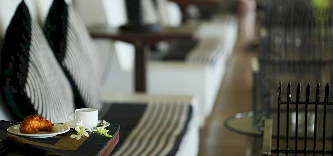 Sitzbereich im Blauen Wasser Hotel und Spa mit Kissen, Croissant, Tasse Kaffee und Blumen