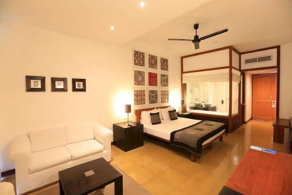 Das Schlafzimmer im Blue Water Hotel und Spa mit einem Bett, einer Couch, Nachttischen und Bildern an der Wand.