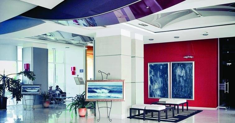 Empfangsbereich des Festa Panorama Hotels mit roter Wand, Kunstwerken und Sitzgelegenheiten.