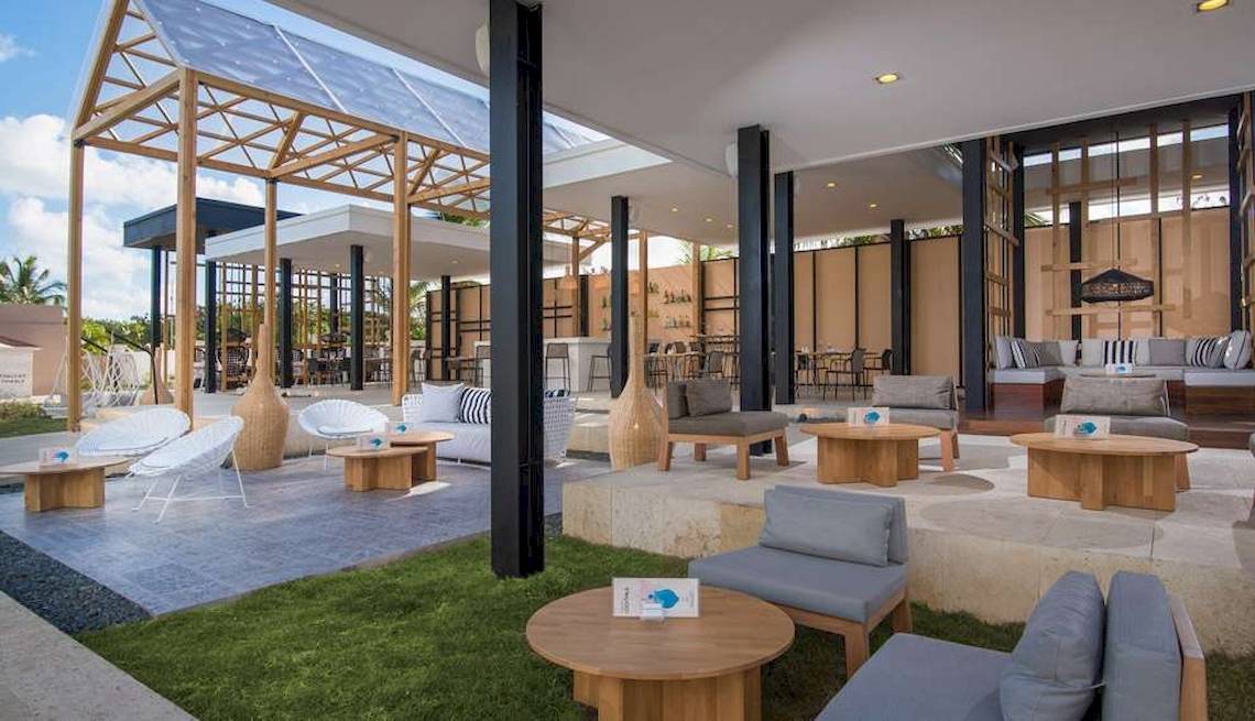 Terrasse des Catalonia Royal Bavaro Hotels mit Holztischen und Stühlen.