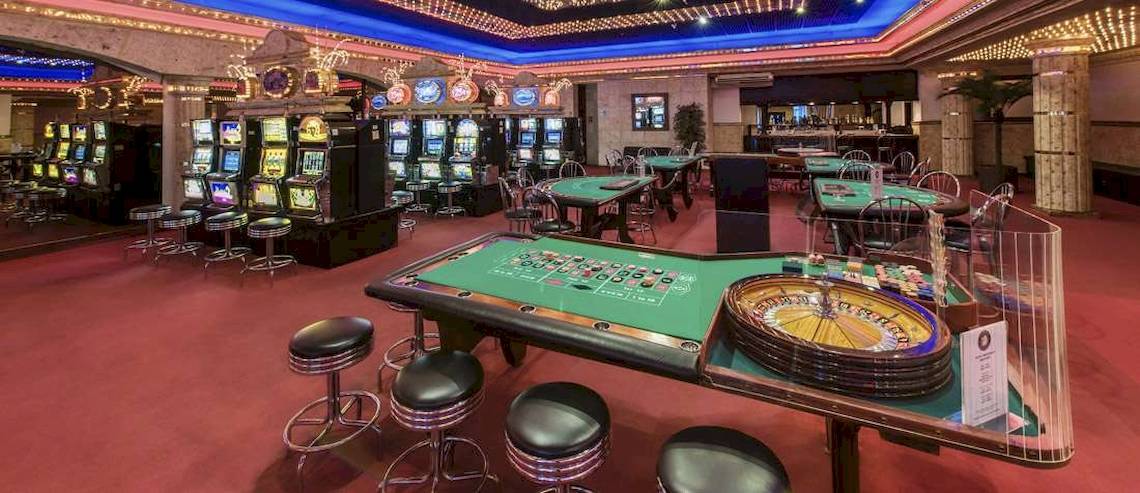 Spielbereich im Casino des Catalonia Royal Bavaro Hotels mit Roulettetisch, Spielautomaten und Tischen.