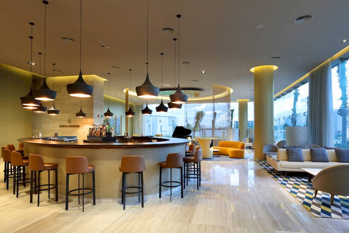 Lobby-Bar im Grand Palladium Costa Mujeres Resort & Spa mit Barhockern und Bartisch.