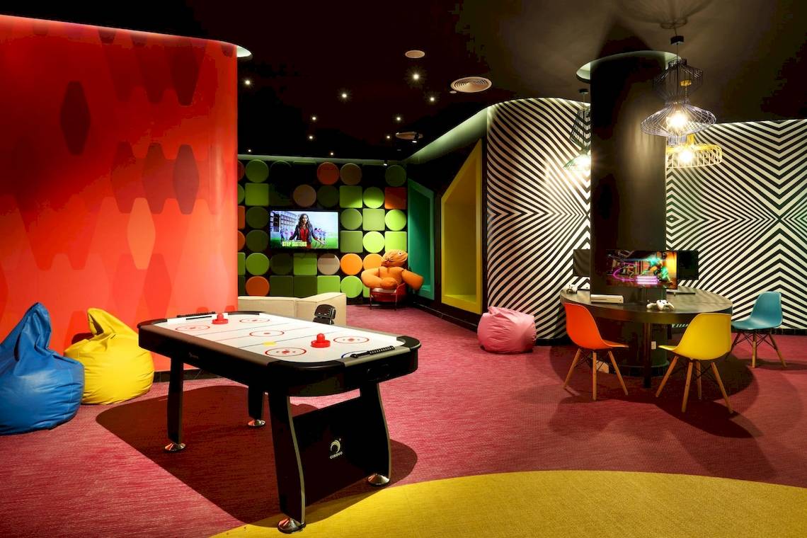 Spielzimmer im Grand Palladium Costa Mujeres Resort mit Tischkicker, Fernsehern und bunten Möbeln.