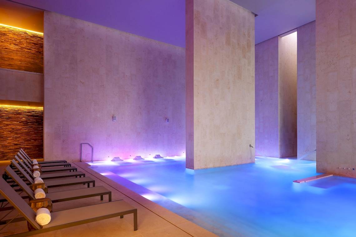 Innenpool des Grand Palladium Costa Mujeres Resort & Spa mit Loungeliegen und blauer Beleuchtung