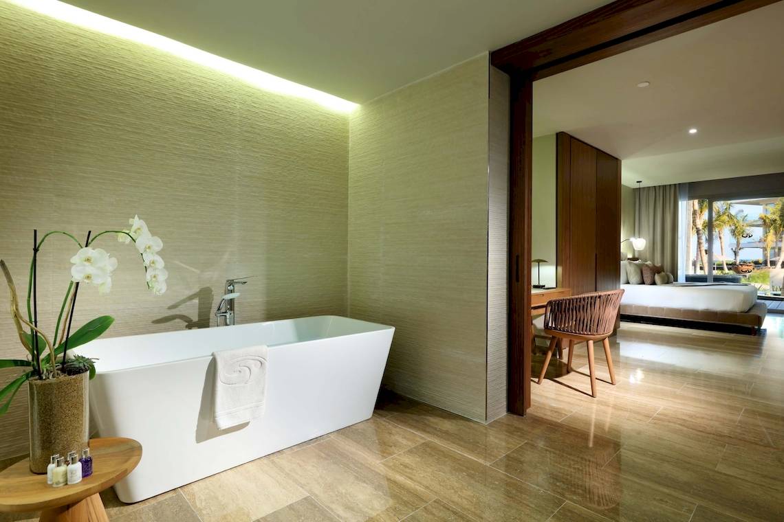 Badezimmer im Grand Palladium Costa Mujeres Resort & Spa mit Badewanne, Orchidee und Blick auf das Schlafzimmer