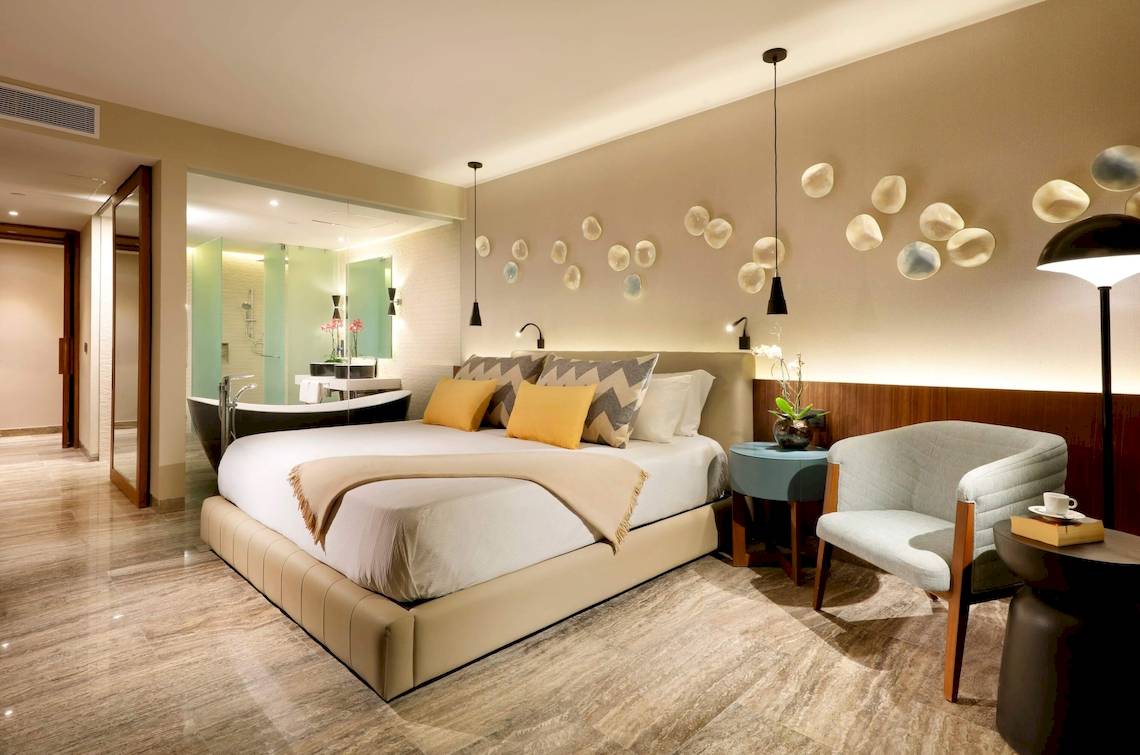Schlafzimmer im Grand Palladium Costa Mujeres Resort mit großem Bett, Wanddekoration und Badewanne.