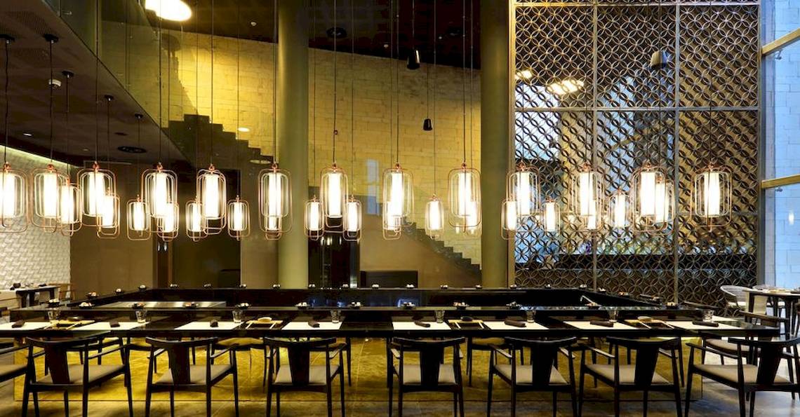 Restaurant im Grand Palladium Costa Mujeres Resort & Spa mit langen Tischen und hängenden Lampen.