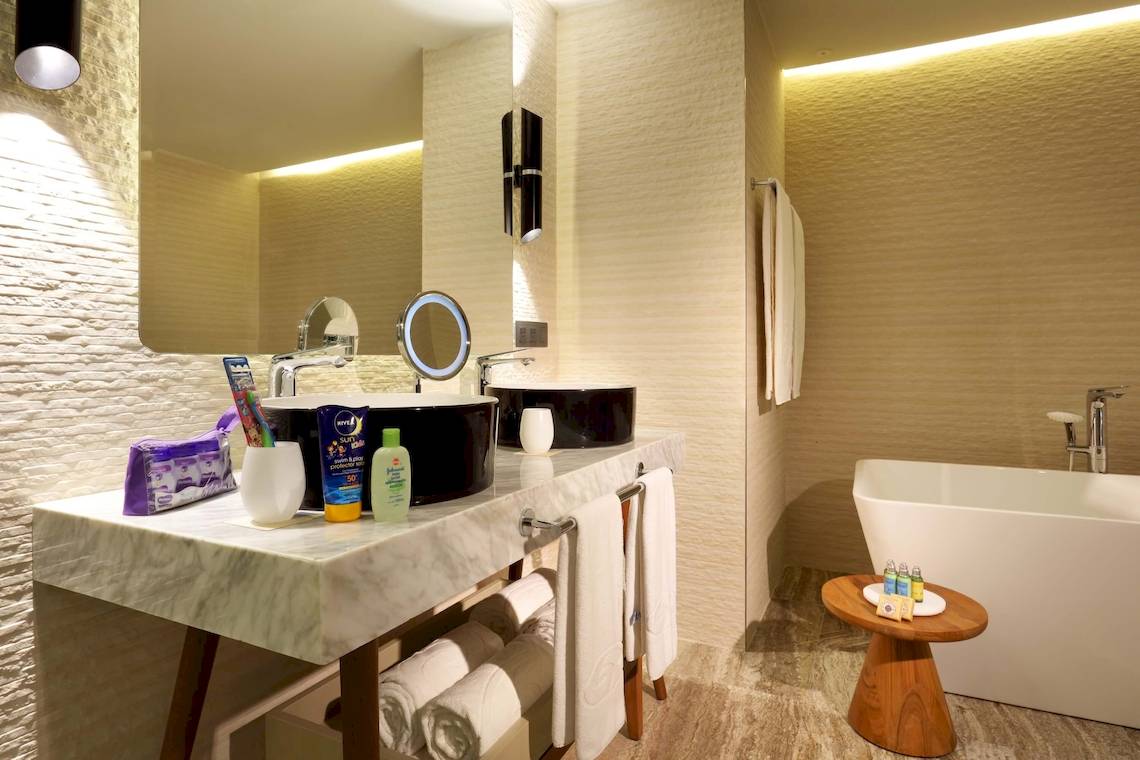 Badezimmer im Grand Palladium Costa Mujeres Resort & Spa mit Marmorarbeitsplatte, zwei Waschbecken und Badewanne.