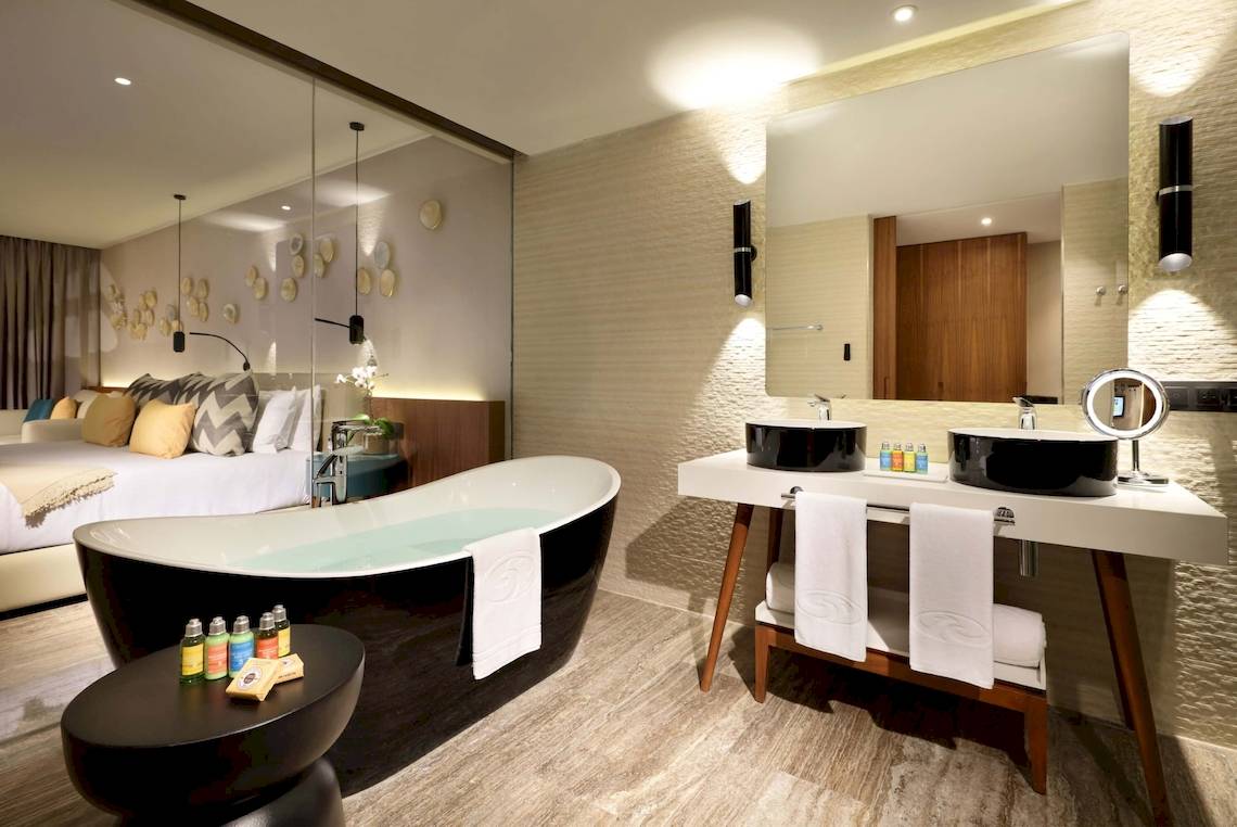 Badezimmer im Grand Palladium Costa Mujeres Resort mit Badewanne, Waschbecken und Bett im Hintergrund.