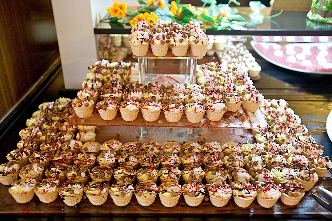 Viele Cupcakes in verschiedenen Farben und Dekorierungen auf mehreren Ebenen in einem Hotel.