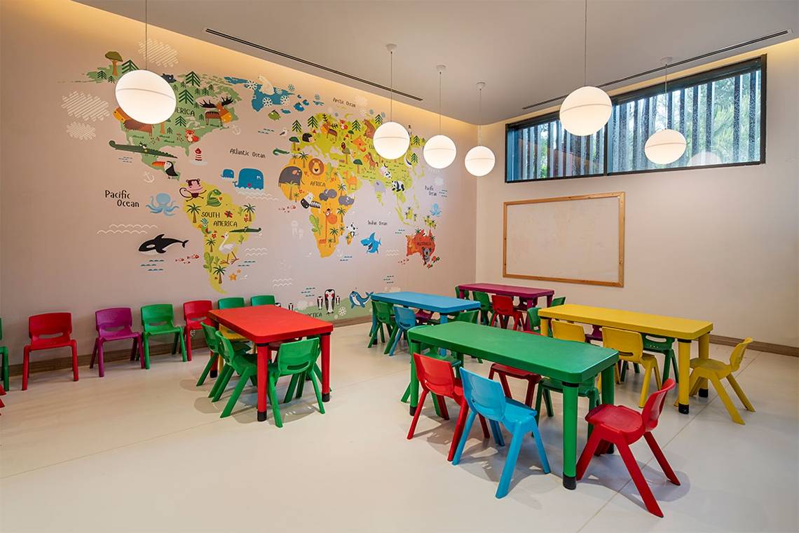 Ein Kinderzimmer mit bunten Tischen und einer Weltkarte an der Wand.