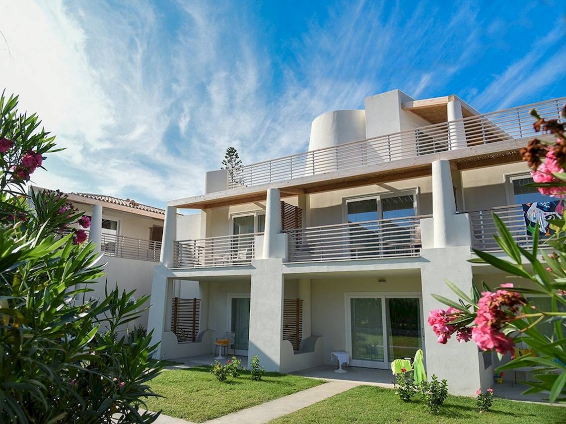 Außenansicht des Baia del Sole Hotels mit Balkonen, Rasen und Blumen im Vordergrund