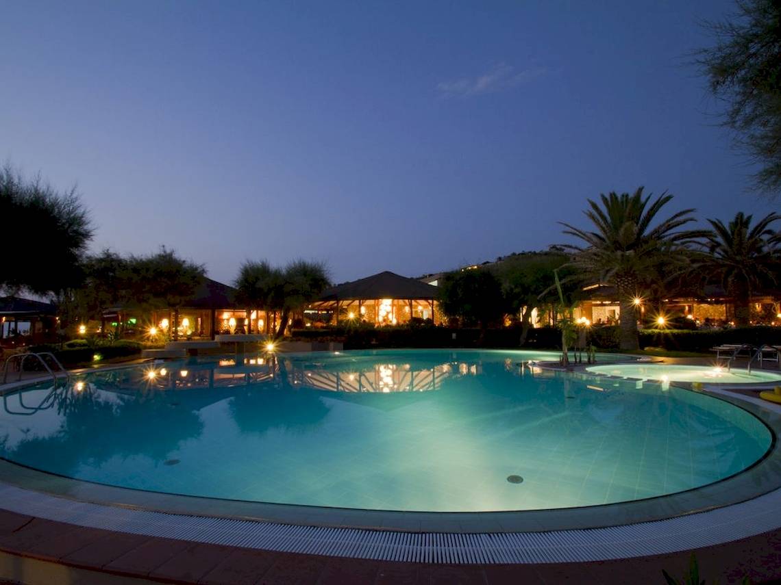Nachtansicht des Swimmingpools des Baia del Sole Hotels, beleuchtet und umgeben von Bäumen