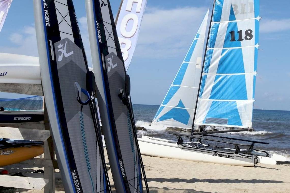 Segelboot und Surfbretter am Strand des Baia del Sole Hotels.