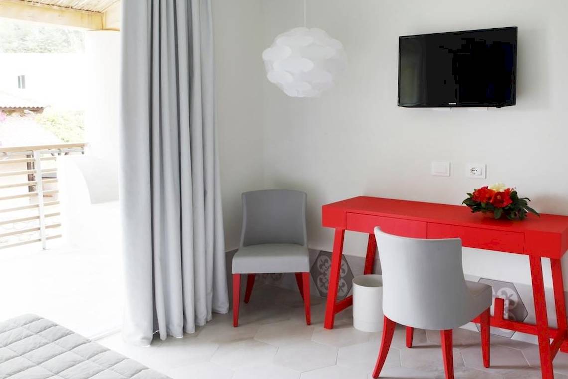 Ein Zimmer im Baia del Sole Hotel mit einem roten Schreibtisch und zwei Stühlen.
