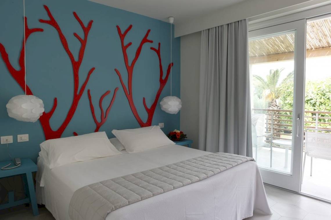 Schlafzimmer im Baia del Sole Hotel mit blauer Wand und roten Dekorationen.