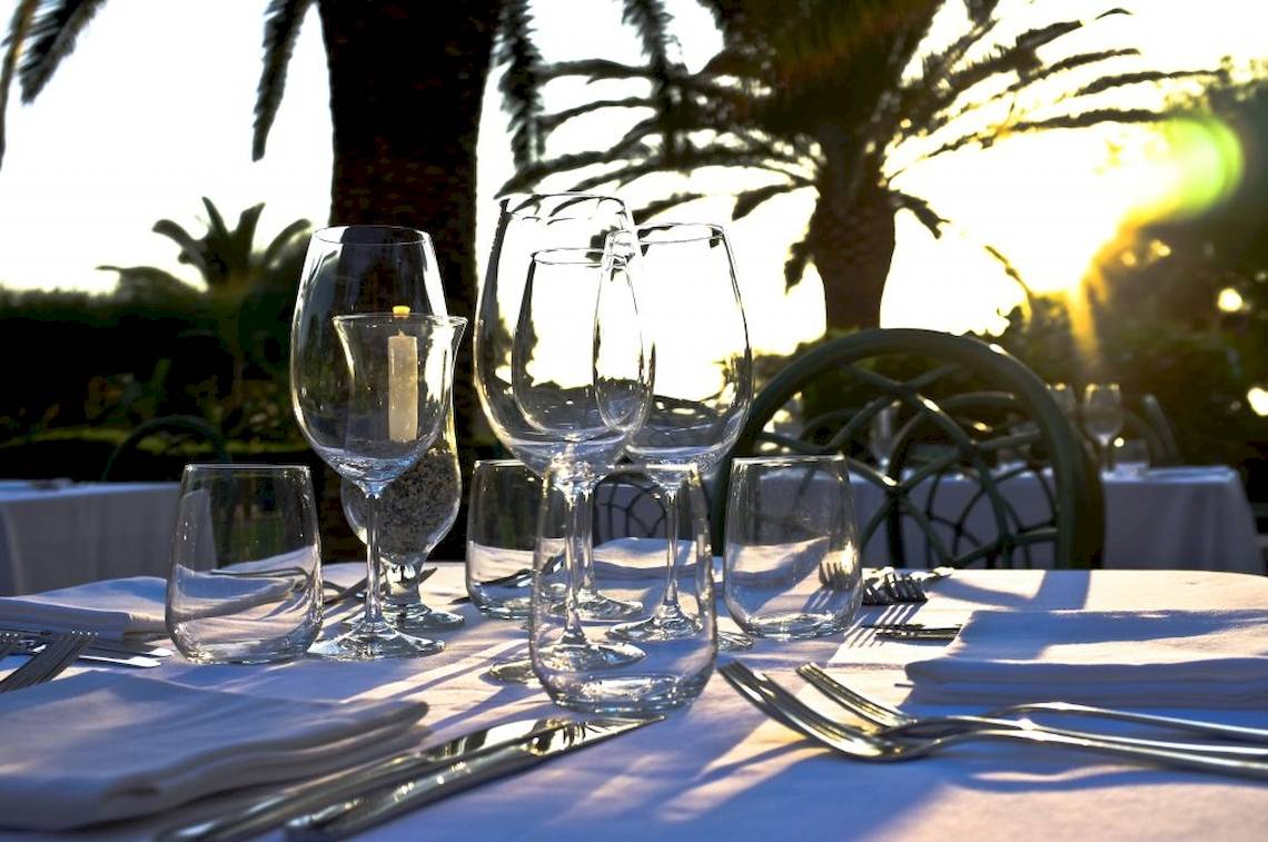 Tisch mit Gläsern und Besteck auf Baia del Sole, vor Sonnenuntergang