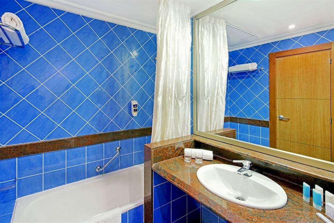 Badezimmer im Mirador Papagayo by LIVVO Hotel mit blauen Fliesen und Badewanne