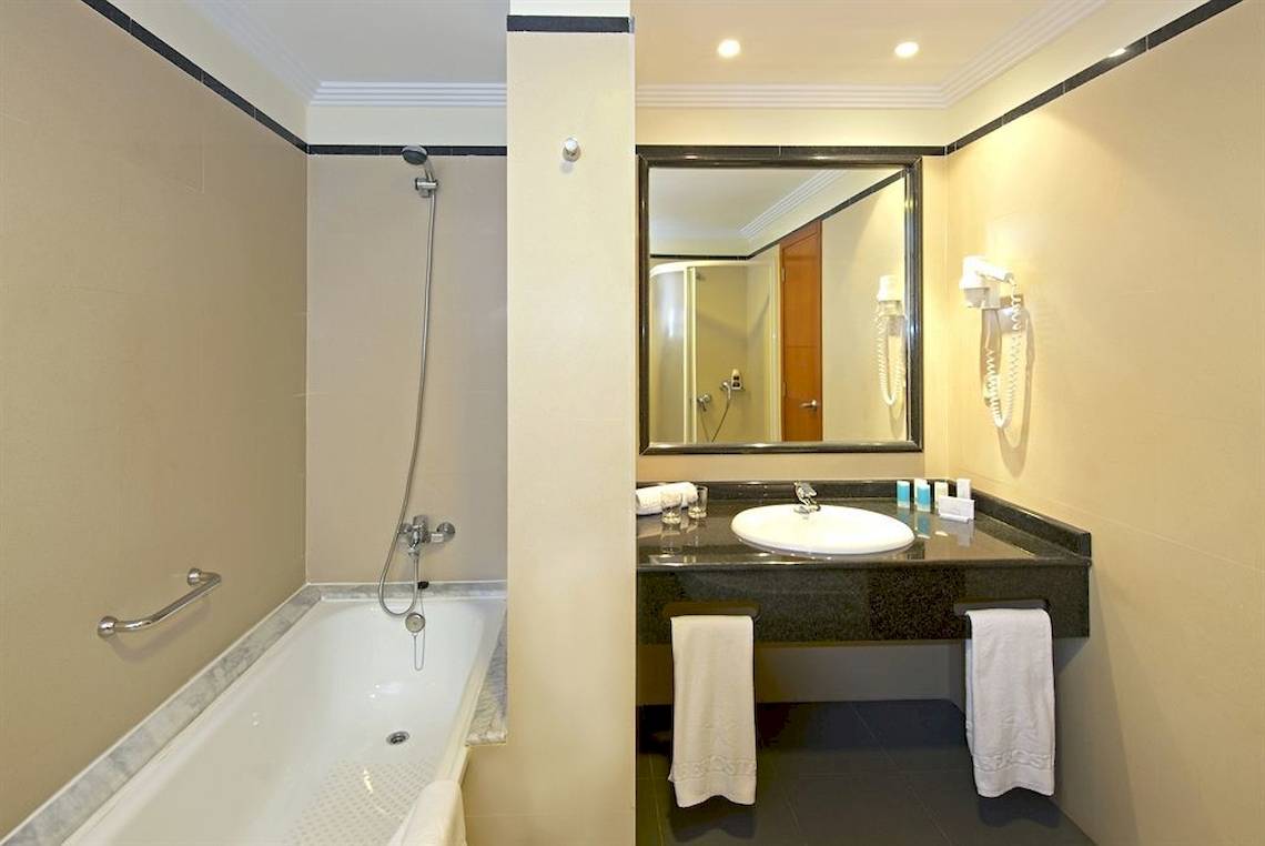 Badezimmer des Mirador Papagayo by LIVVO Hotels mit Badewanne, Waschbecken und Spiegel.