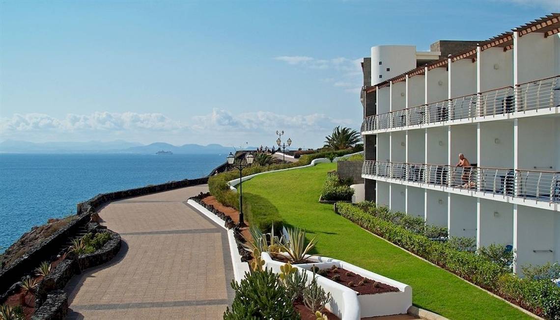 Außenansicht des Mirador Papagayo by LIVVO Hotels mit Blick auf das Meer und eine Person auf dem Balkon.