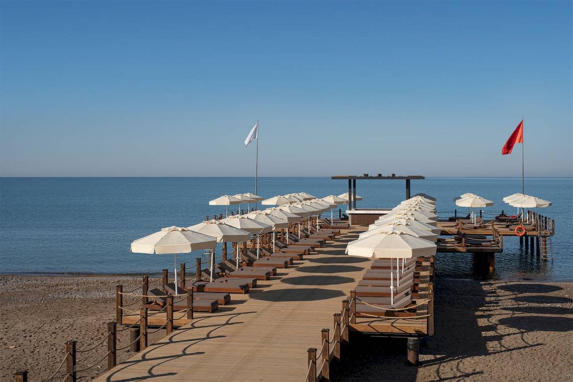 Voyage Belek Golf & Spa, Strand mit Sonnenschirme Sonnenliegene