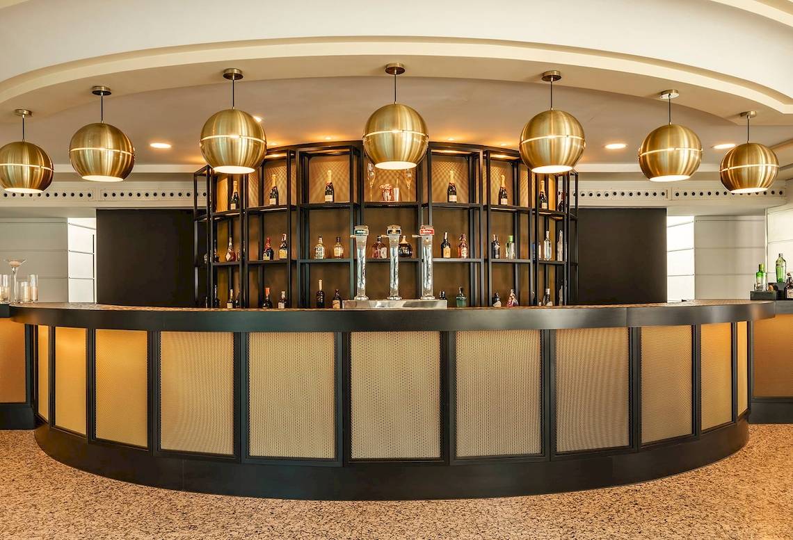 Lobby Bar im Sarena de Muro Resort Mallorca mit goldenen Kronleuchtern und einer großen Bartheken.