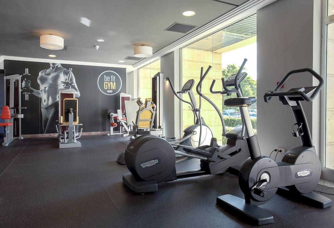 Fitnessstudio im Sarena de Muro Resort Mallorca mit Technogym-Geräten und Blick auf die Außenlandschaft.