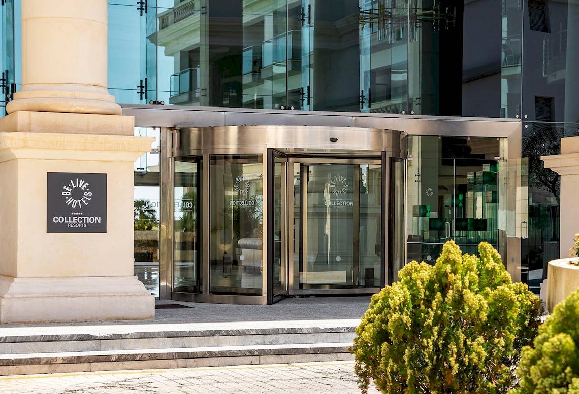 Vorderansicht des Sarena de Muro Resort Mallorca mit Drehtüreingang und Logo