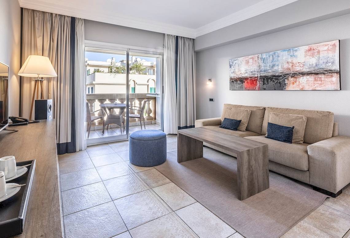 Wohnbereich des Sarena de Muro Resort Mallorca Hotels mit einem Sofa, einem Tisch und einem Balkon.