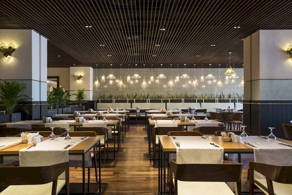 Innenbereich des Restaurants im Voyage Sorgun Hotel mit gedeckten Tischen und dekorativen Beleuchtungskörpern.