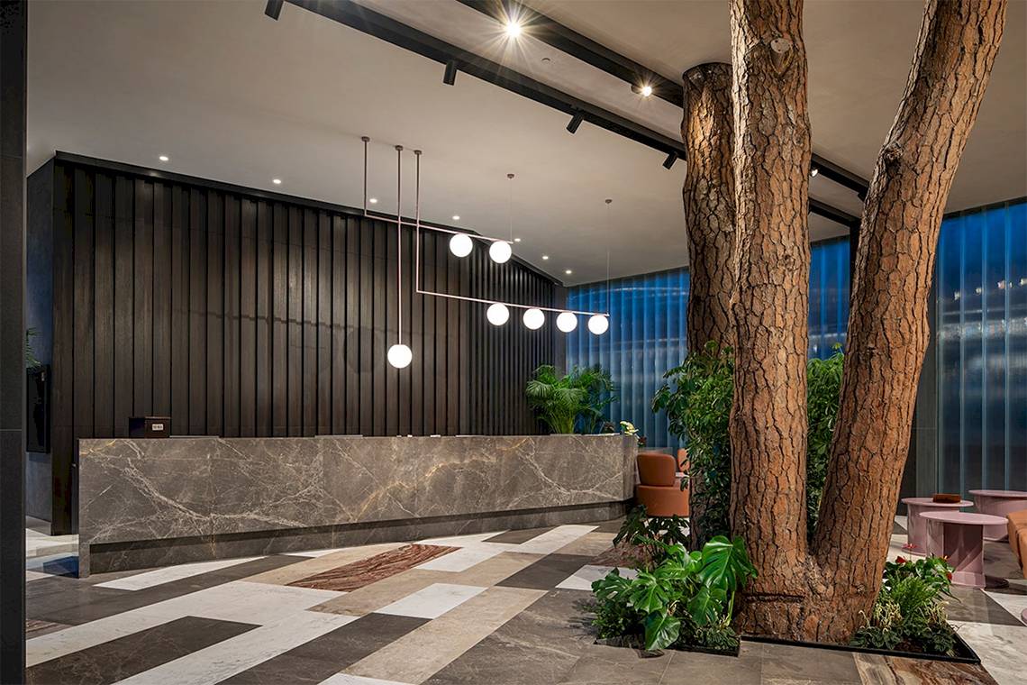 Lobby des Voyage Belek Golf & Spa Hotels mit Marmorrezeption und modernen Möbeln.