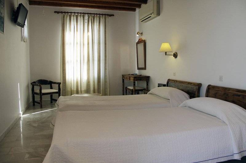 Zwei Betten im Zimmer im Vienoulas Garden Hotel mit weißem Bettlaken und Kissen.
