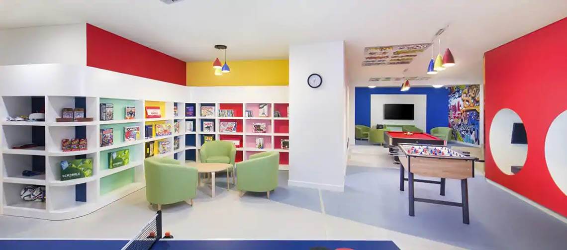 Das farbenfrohe Kinderzimmer des Hilton Ras Al Khaimah Beach Resort mit Bücherregalen, Tischen, Stühlen und Spielen.