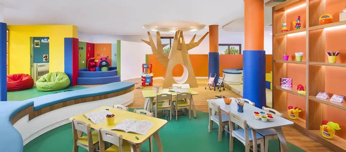 Kinderbereich im Hilton Ras Al Khaimah Beach Resort mit bunten Farben, Tischen, Stühlen und Spielzeug.