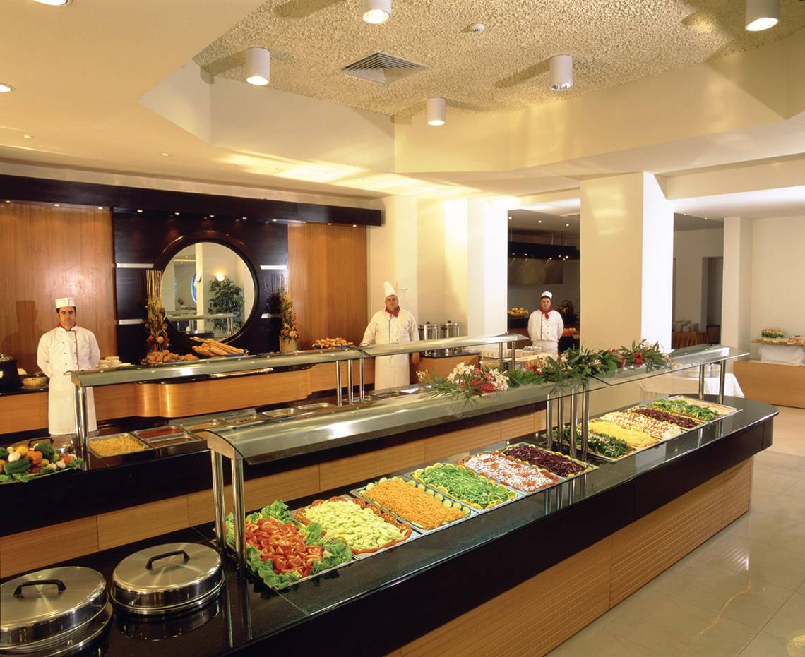 Buffettisch im Hotel Calypso Beach mit verschiedenen Gerichten und Köchen im Hintergrund.