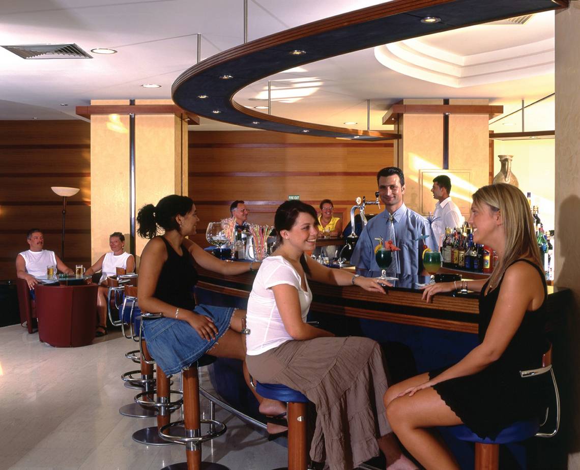 Gäste sitzen an der Bar des Calypso Beach Hotels und unterhalten sich mit dem Barkeeper.