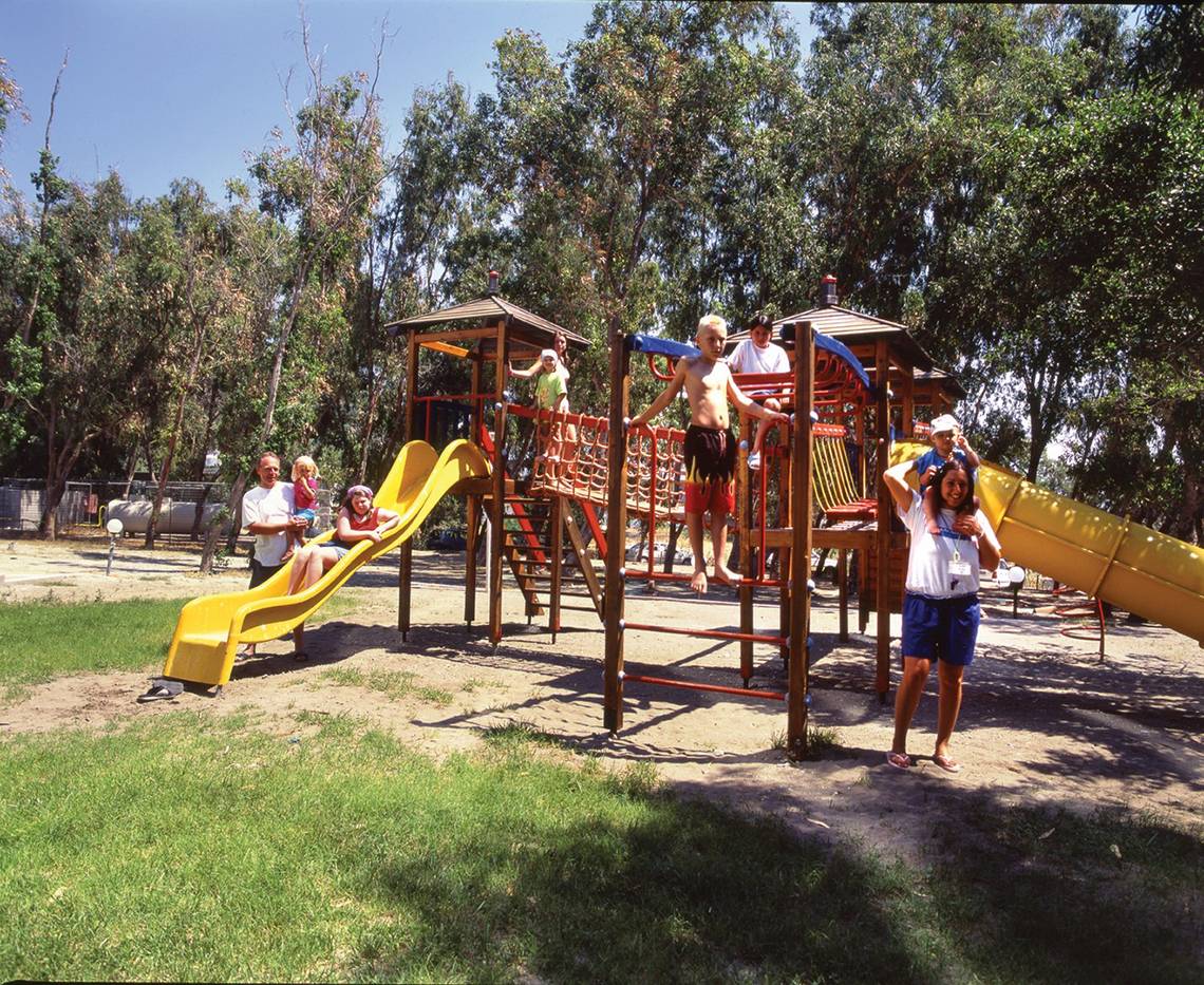Familie genießt einen Tag auf dem Spielplatz im Freien, mit Rutschen und Klettergerüsten