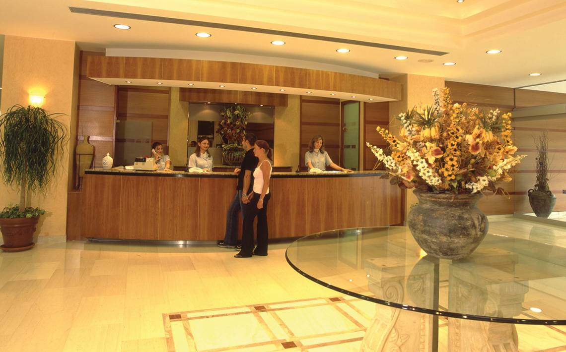 Receptionsbereich im Calypso Beach Hotel mit drei Angestellten und zwei Gästen.