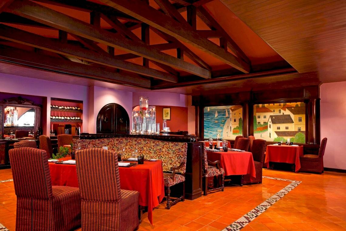 Innenansicht des Restaurants im Le Meridien Phuket Beach Resort mit roten Tischen und Stühlen.