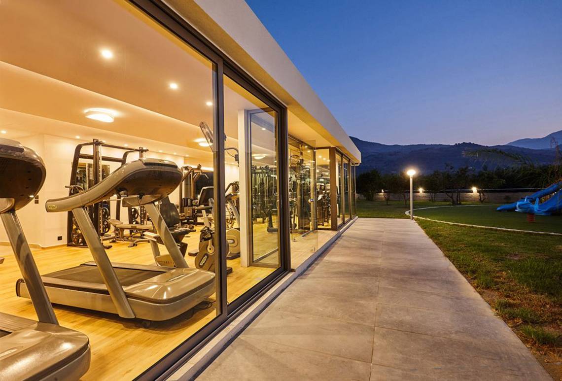 Außenansicht des Fitnessraums von Annas Haus mit Trainingsgeräten und Panoramablick auf die Berge